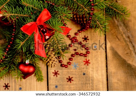 Christmas Border - fir branches with red baubles, bells and snowflakes on a wooden background.