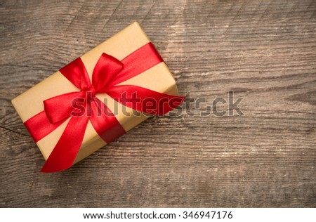 Gift box with red ribbon on wooden background with copy space