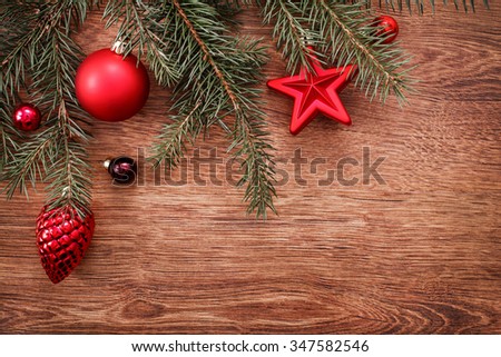 Red Christmas ornaments and fir tree branch on a rustic wooden background. Xmas card. Happy New Year. Top view with copy space