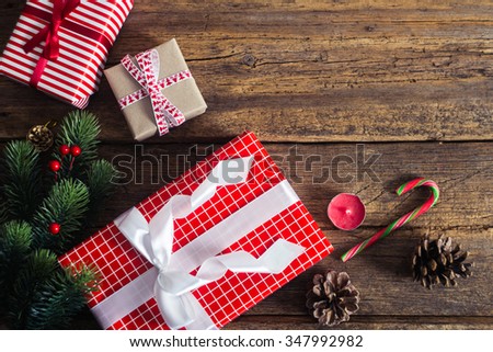 Christmas presents on a wooden background with candy cane, fir branches, candle, cones.