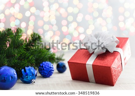 Decorative red gift box with a large silver bow and background bokeh of twinkling party lights