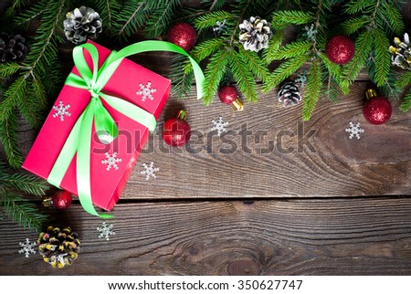 Christmas gift in red box with ribbon and decorations at dark wooden table. Top view, copy space.