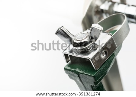 Detail of a wing screw on a strange cutting machine, on white background