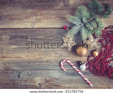 Christmas or New Year rustic wooden background with toy decorations, candy cane and fur tree branch, top view, copy space