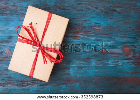 Gift box with red ribbon on wooden background