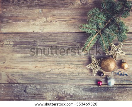Christmas or New Year rustic wooden background with toy decorations and fur tree branch, top view, copy space