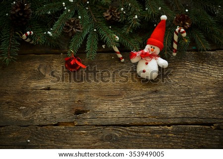 Christmas tree branches with christmas decorations and snowman on wooden texture. Winter holidays background