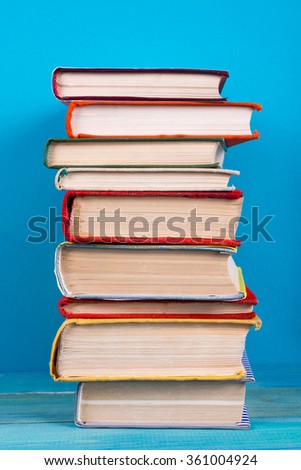 Stack of colorful books, grungy blue background, free copy space Vintage old hardback books on wooden shelf on the deck table, no labels, blank spine. Back to school. Education background