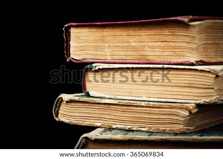 A few old books stacked in a pile on a black background
