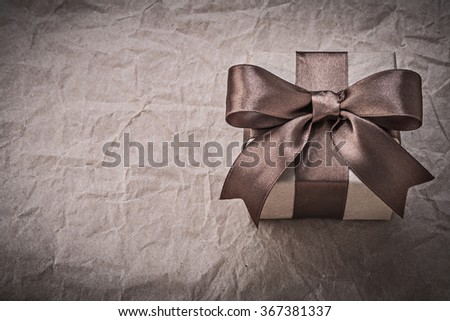 Giftbox with brown bow on wrapping paper holidays concept.