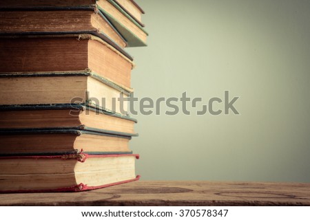 Still life with dirty and worn book stack on wooden table