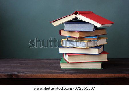 Pile of books in color covers on a dark  wooden table.
