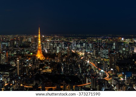 Cityscape of Tokyo at night, as seen from the top of one of the highest buildings in Roppongi Hills, with the illuminated Tokyo Tower glowing in the dark. Long exposure.