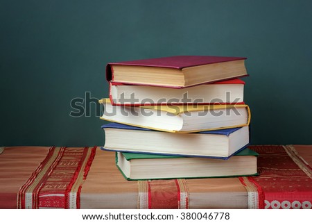 Stack books with color covers on the table with a red tablecloth.