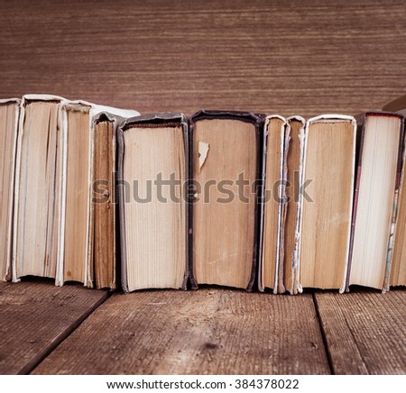 Old shabby books on wooden background. Sepia