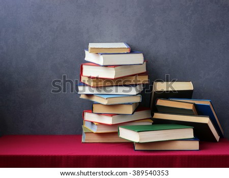A stack of books in the colored covers on the table with a red tablecloth. Still life with books.