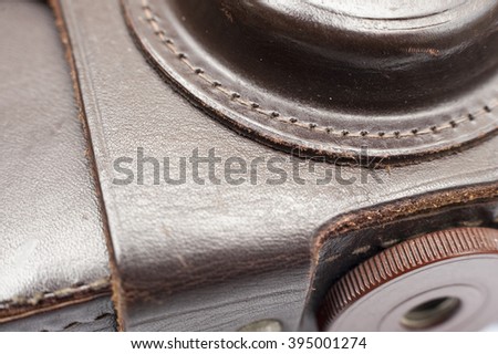 Macro photo of a vintage brown cover for small-format film camera. View from the mounting screw. Focus is on the line connecting the portion of the leather cover protects the lens with the main part.