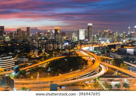 Aerial view highway interchanged with city downtown background at twilight, long exprosure