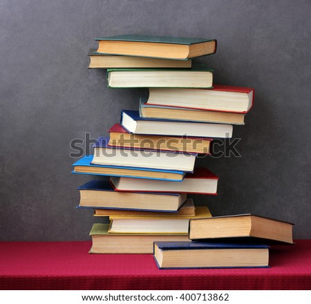 Stack of books in the colored covers on the table with a red tablecloth. Still life with books.