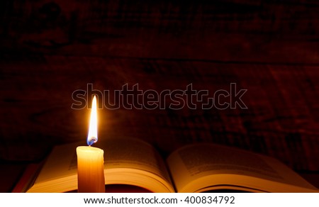 book on a wooden table with candlelight