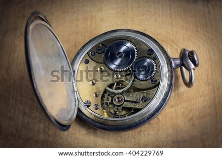 Pocket watch inside on wooden desk with wheels and springs golden color