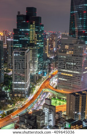 A shot from one of the high rises building in Tokyo which focuses on the illuminated expressway and the lights of the vehicle