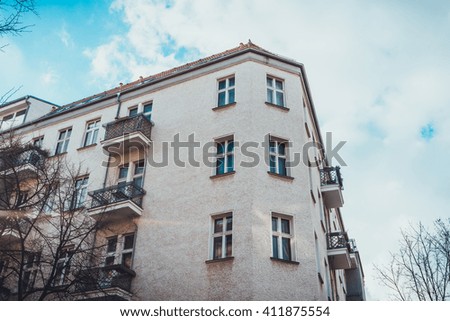 Low Angle Architectural Exterior of Corner of Modern Low Rise Residential Apartment Building with Small Balconies and Surrounded by Bare Trees and Blue Sky with Clouds