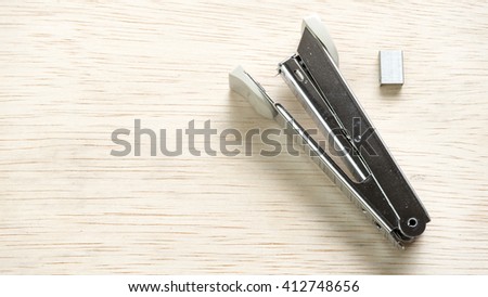 Stainless steel stapler on wooden surface. Isolated on empty background. Slightly de-focused and close-up shot. Copy space.

