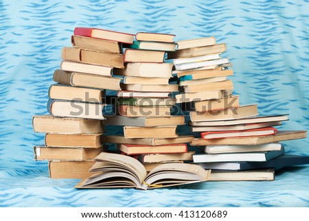 Open book, stack of hardback books  on blue cloth. Back to school. Copy space