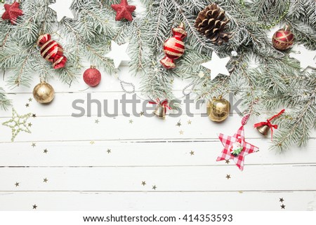 Christmas or New Year background: fur-tree branches, colorful glass balls, decoration and glittering stars on white wood, top view, copy space.