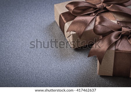 Boxed gifts in brown wrapping paper on grey background celebrations concept.