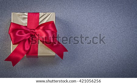 Present box wrapped in glittery paper on grey background holidays concept.