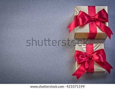 Boxed presents with red knots on grey background copy space holidays concept.
