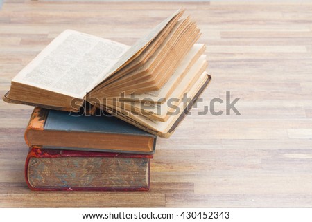 Books stack with open one on wooden table background