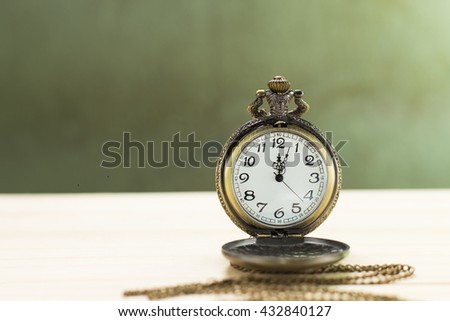 Antique clock on the wooden floor and green wall Background.