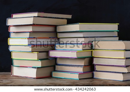 Books in stacks on the table in the background of a school blackboard. Back to school. 