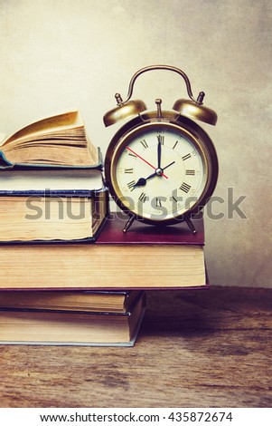 A pile of books and alarm clock ,with a retro effect.
