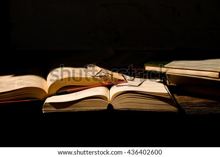 Open books with reading glasses on black background