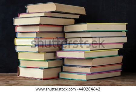 Books in stacks on the table in the background of a school blackboard. Back to school.