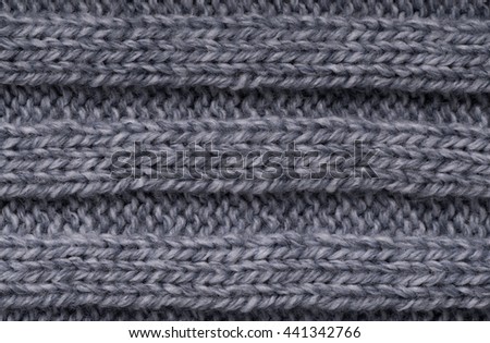 The texture of a knitted woolen cloth is gray, with a ribbed pattern stripes. background