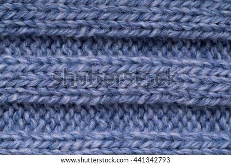 The texture of a knitted woolen cloth is blue, with a ribbed pattern stripes. background