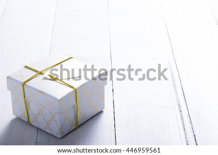 white gift box with golden string and card on bright wood table