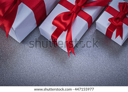 Boxed gifts with tied red ribbons on grey surface directly above holidays concept.