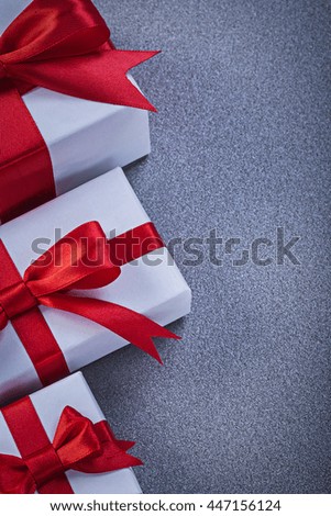 Boxed gifts with tied red bows on grey surface holidays concept.