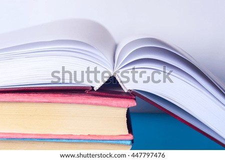 Open book, stack of colorful hardback books on light table. Back to school. Copy space for text. Toned image.