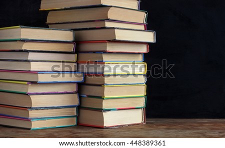 Books in stacks on the table in the background of a school blackboard. Back to school. Right empty space for Your text.