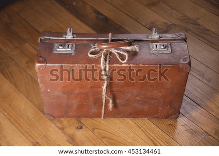 Old brown cardboard suitcase on background wooden floor