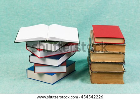 Open book, stack of hardback books on blue table. Back to school. Copy space.