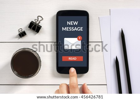 New message concept on smart phone screen with office objects on white wooden table. All screen content is designed by me.