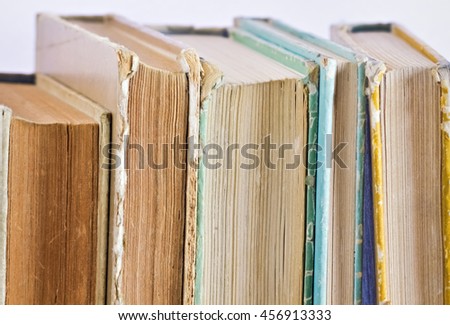 Closeup of several old books vertically placed on the shelf